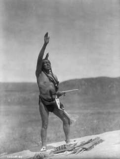  Dakota man, wearing breechcloth, holding pipe, with right 